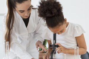 front-view-female-scientist-teaching-girl-look-through-microscope